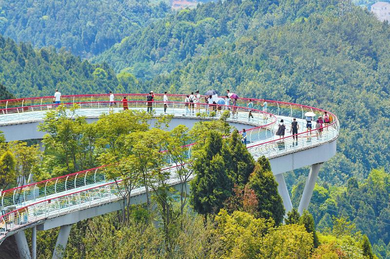 6月15日,游客在成都市龙泉山城市森林公园的丹景台上俯瞰城市美景