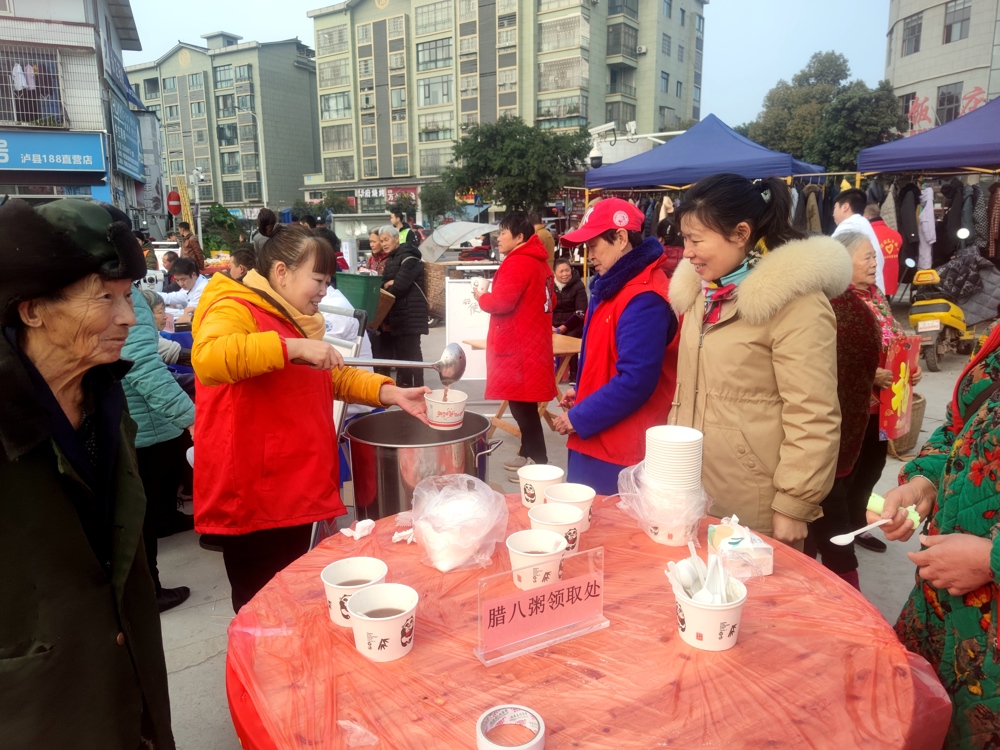 泸县潮河镇瓦子社区志愿者为返乡农民工雷文芳（右一）盛上腊八粥