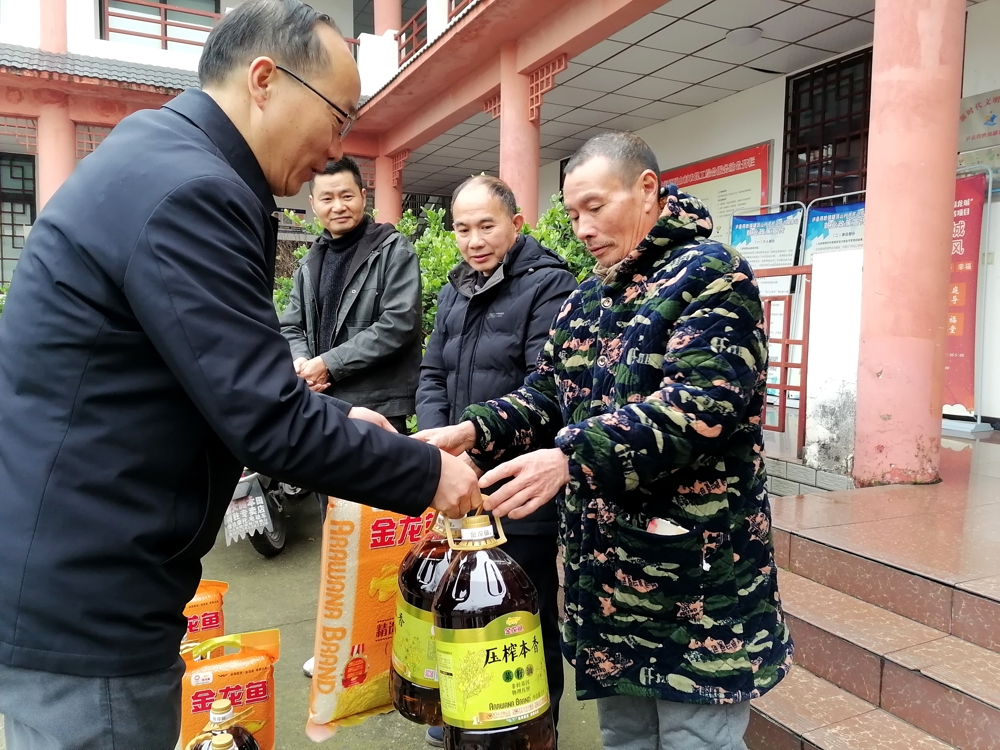 泸县得胜镇便民服务中心主任刘云贵（左一）为农民工留守家人代表送上暖心慰问物品